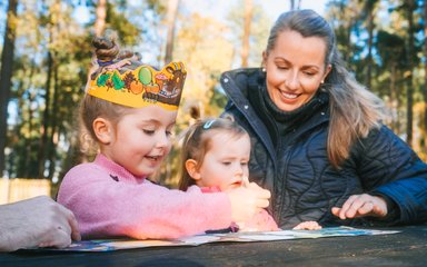 woman and young kids looking at leaflets on a forest bench